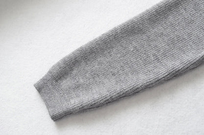 Stylish knitwear vest in a classic black or neutral colour, featuring a V-neck collar and long sleeves for a polished, versatile look.