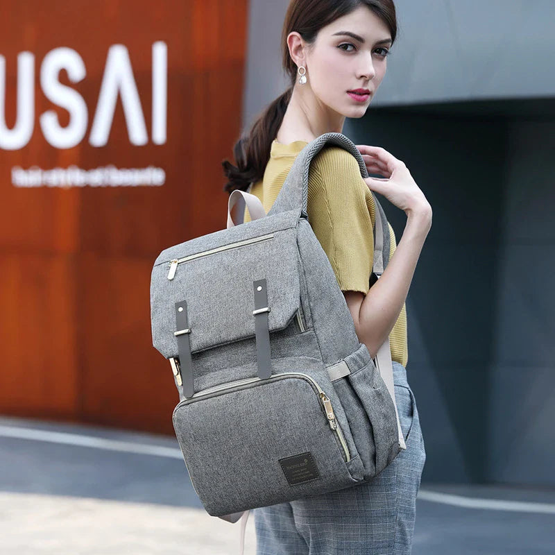 Versatile mum's backpack with pink color, featuring side pockets, zippered compartments, and stroller attachment hooks