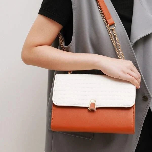 Stylish quilted vegan leather shoulder bag in orange color with unique lock and chain decoration