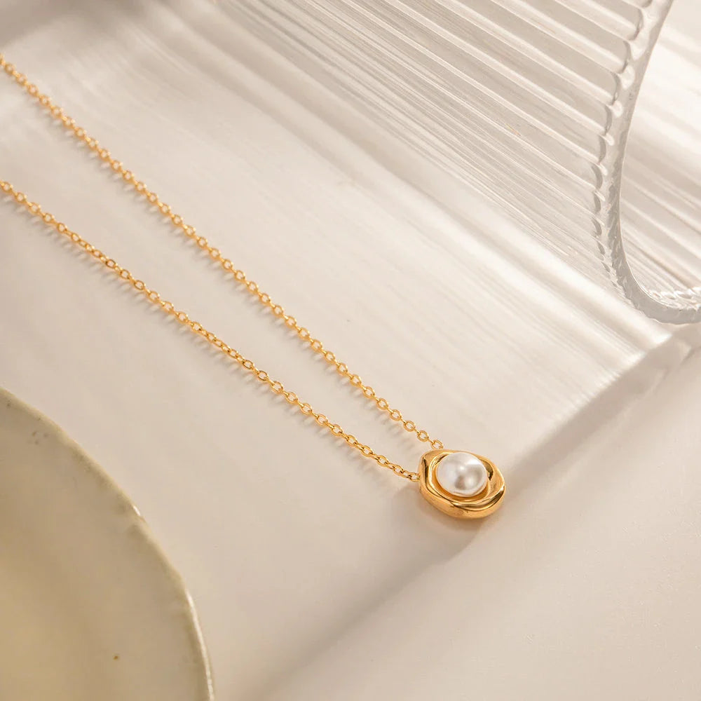 Elegant stainless steel necklace with a unique, irregular pearl pendant in a gold color, featuring a contemporary geometric design