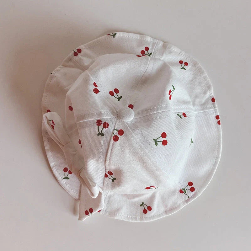 A charming bucket hat for kids featuring a delightful fruit print and cute bow detail, providing excellent sun protection and comfort.