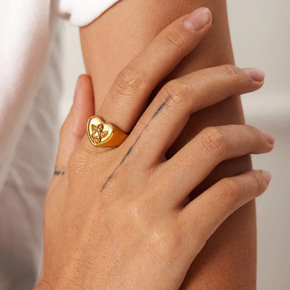 Closeup of a gold plated stainless steel ring with a heart and angel design, a classic and elegant accessory