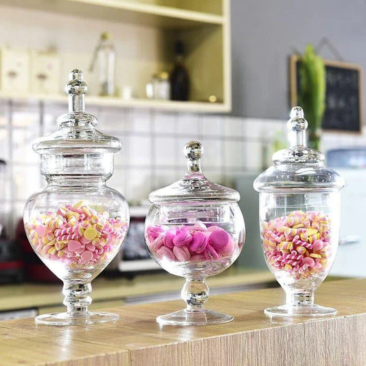 A transparent glass candy jar with a secure lid, perfect for serving sweets and treats at a wedding celebration.