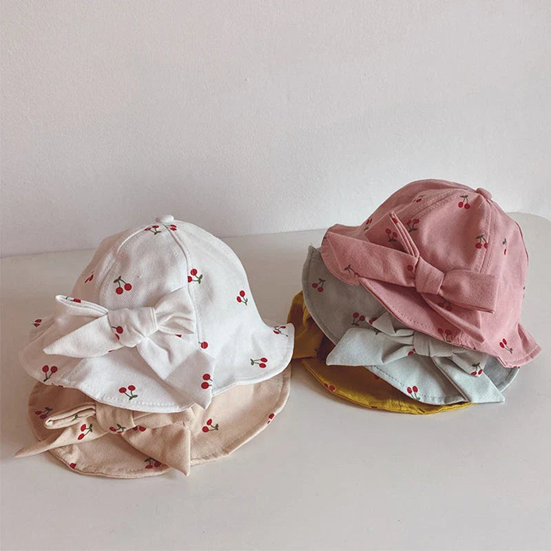 A charming bucket hat for kids featuring a delightful fruit print and cute bow detail, providing excellent sun protection and comfort.