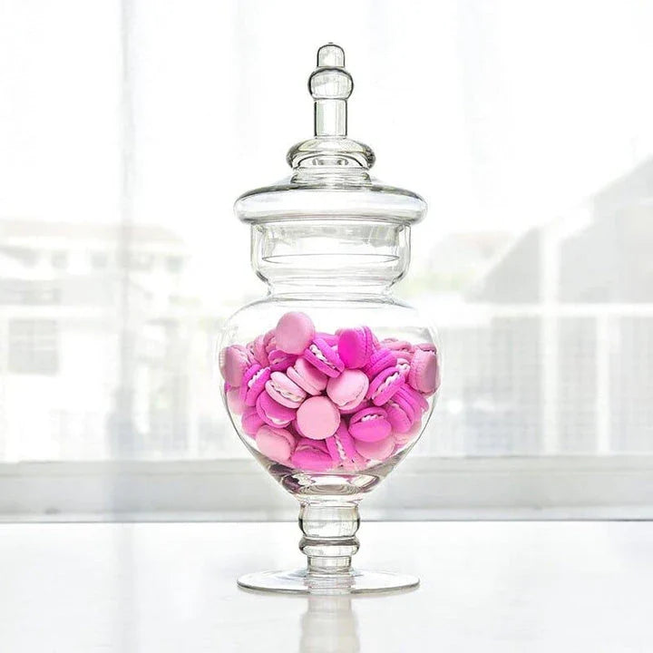 A transparent glass candy jar with a secure lid, perfect for serving sweets and treats at a wedding celebration.