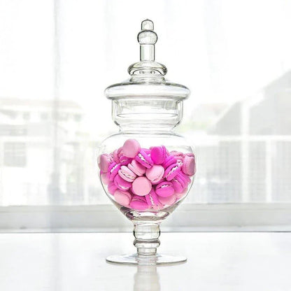 A transparent glass candy jar with a secure lid, perfect for serving sweets and treats at a wedding celebration.
