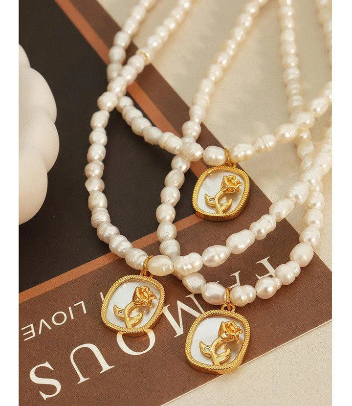 Exquisite gold-toned necklace featuring a delicate chain with embossed floral design and natural freshwater pearls accented by zirconia stones