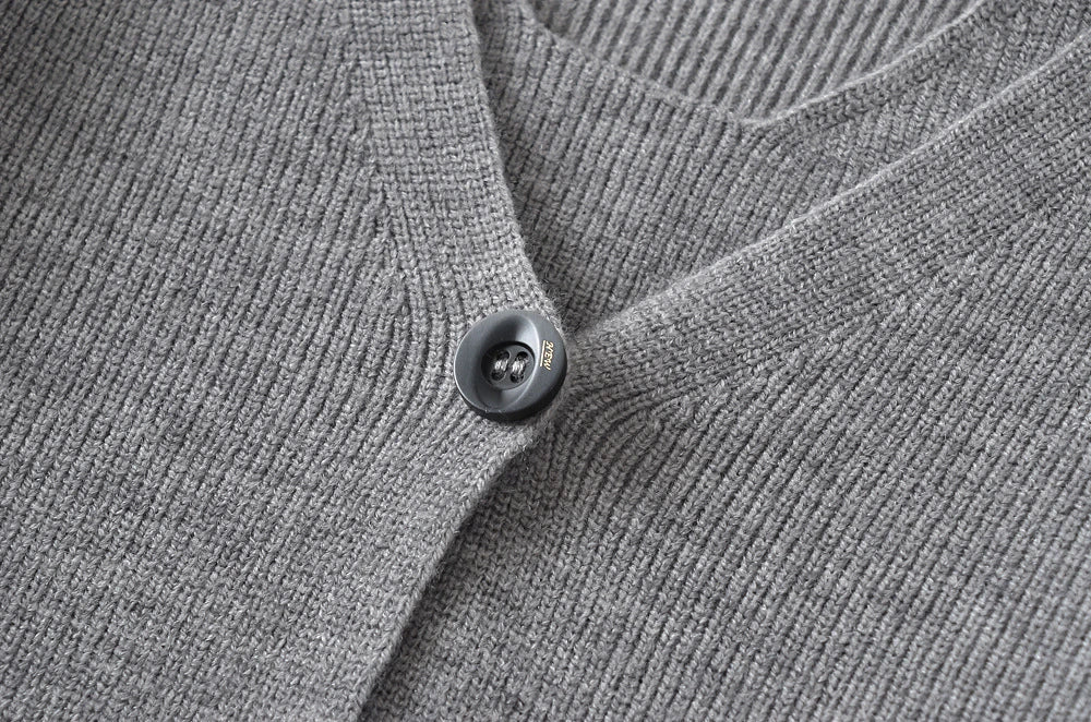 Stylish knitwear vest in a classic black or neutral colour, featuring a V-neck collar and long sleeves for a polished, versatile look.