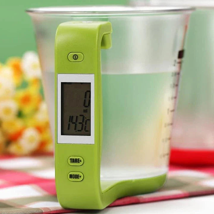 A green digital measuring cup with an LCD display integrated into the handle, designed in New Zealand for precise kitchen measurements