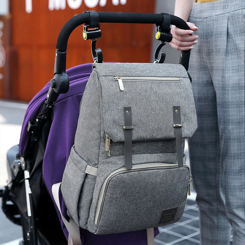 Versatile mum's backpack with pink color, featuring side pockets, zippered compartments, and stroller attachment hooks