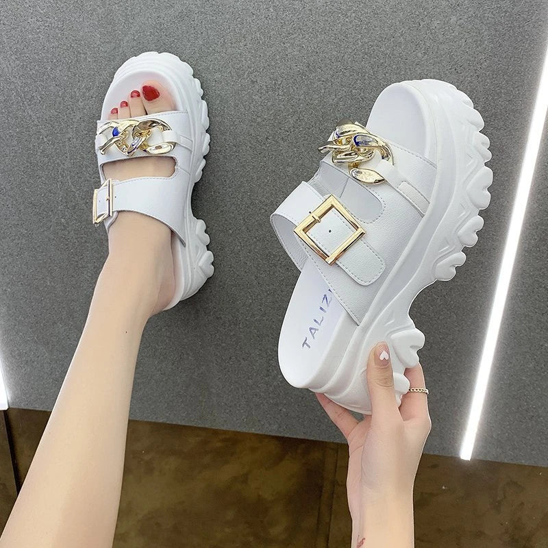 A pair of white, sponge cake-inspired sandals with a metal buckle, showcasing a unique and stylish Kiwi-inspired design.