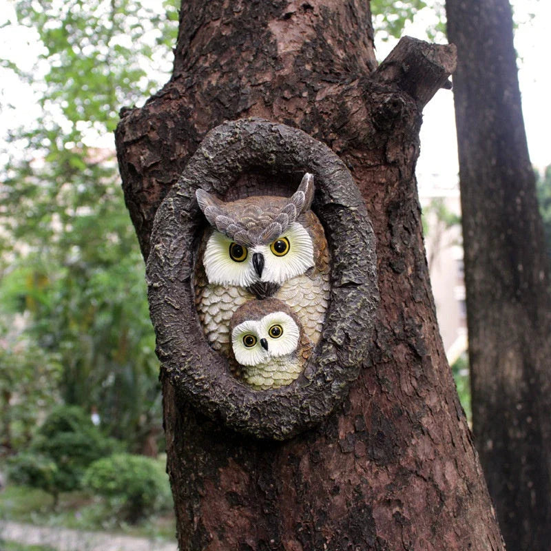 Charming resin mother and child owl ornament hanging from a tree branch in a Kiwi garden