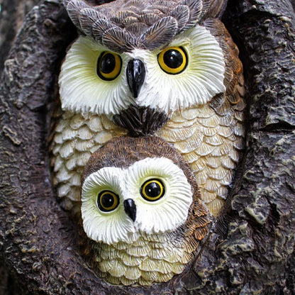 Charming resin mother and child owl ornament hanging from a tree branch in a Kiwi garden