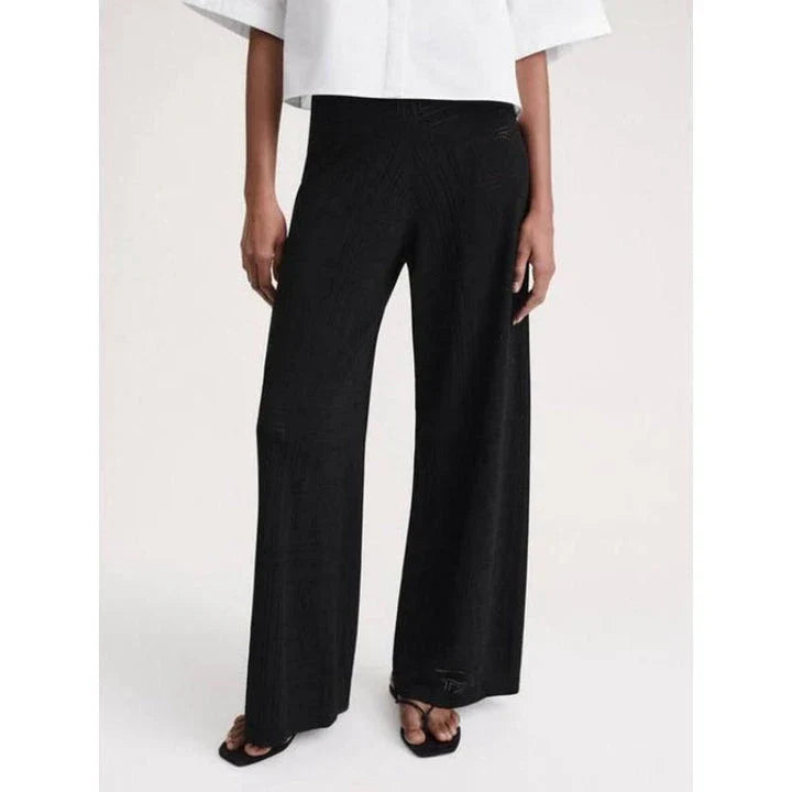 High-waist hollow-out knit trousers in a black color, featuring a straight, wide-leg cut and a sophisticated pattern