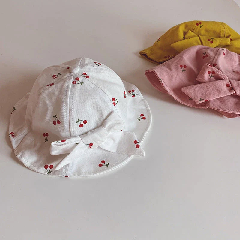 A charming bucket hat for kids featuring a delightful fruit print and cute bow detail, providing excellent sun protection and comfort.