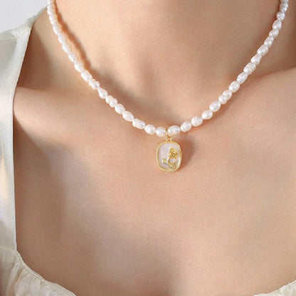 Exquisite gold-toned necklace featuring a delicate chain with embossed floral design and natural freshwater pearls accented by zirconia stones