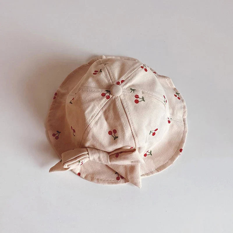 A charming bucket hat for kids featuring a delightful fruit print and cute bow detail, providing excellent sun protection and comfort.