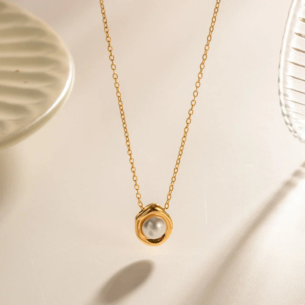 Elegant stainless steel necklace with a unique, irregular pearl pendant in a gold color, featuring a contemporary geometric design