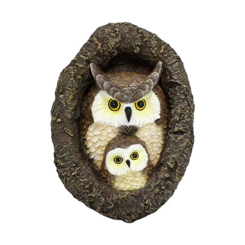 Charming resin mother and child owl ornament hanging from a tree branch in a Kiwi garden