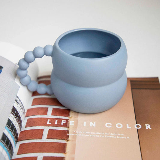 Handcrafted ceramic mug in a soothing beige and blue color palette, featuring a modern Nordic design