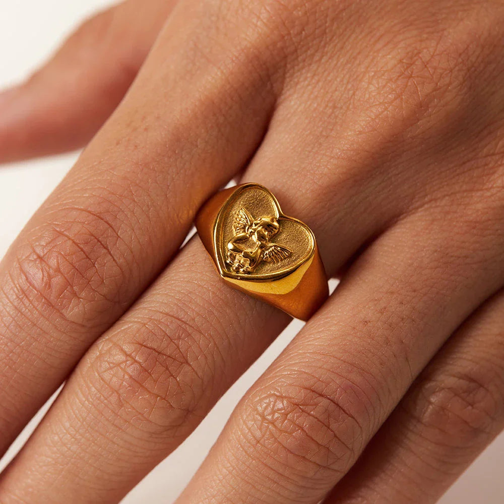 Closeup of a gold plated stainless steel ring with a heart and angel design, a classic and elegant accessory