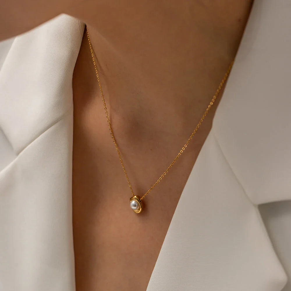 Elegant stainless steel necklace with a unique, irregular pearl pendant in a gold color, featuring a contemporary geometric design