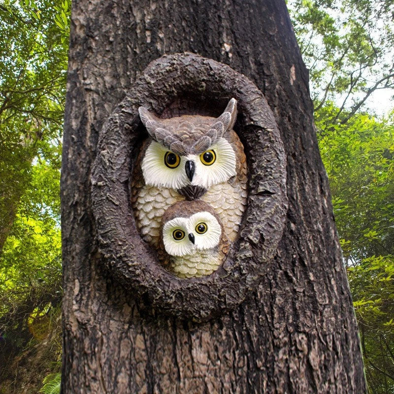 Charming resin mother and child owl ornament hanging from a tree branch in a Kiwi garden