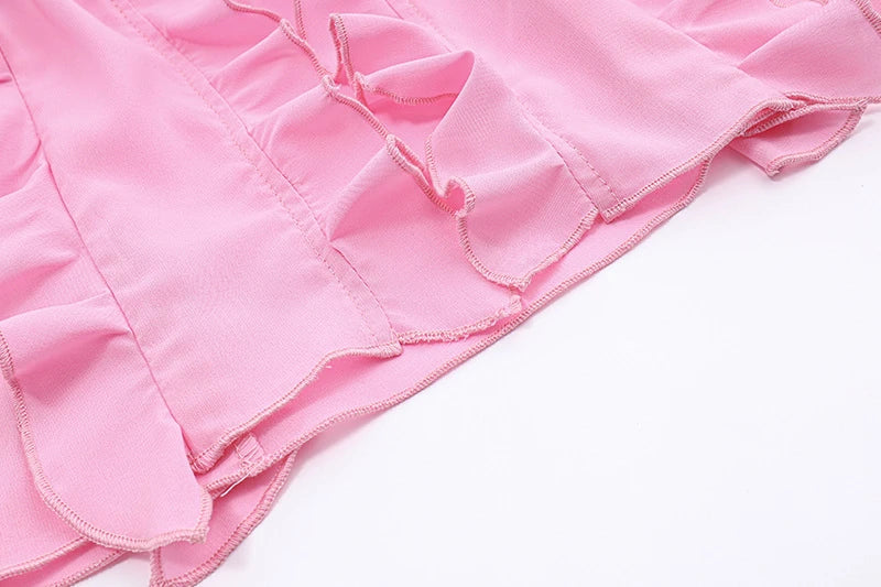 A pink ruffled crop top with a heart-shaped bow accent, made from stretch chiffon fabric for the modern Kiwi girl's style.