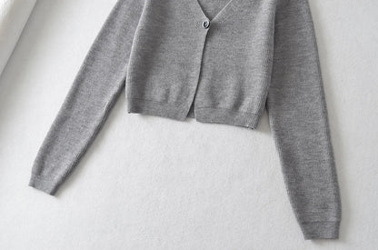 Stylish knitwear vest in a classic black or neutral colour, featuring a V-neck collar and long sleeves for a polished, versatile look.