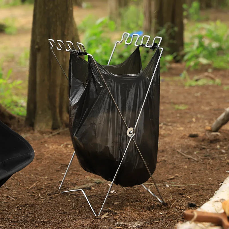 Silver folding stainless steel garbage bag holder bracket on a wooden surface.