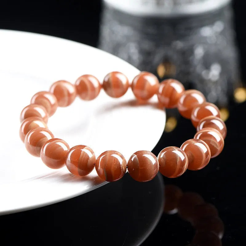 Natural old mine rhodochrosite round bead bracelet on wrist, showing geometric design and Ruyi symbol.