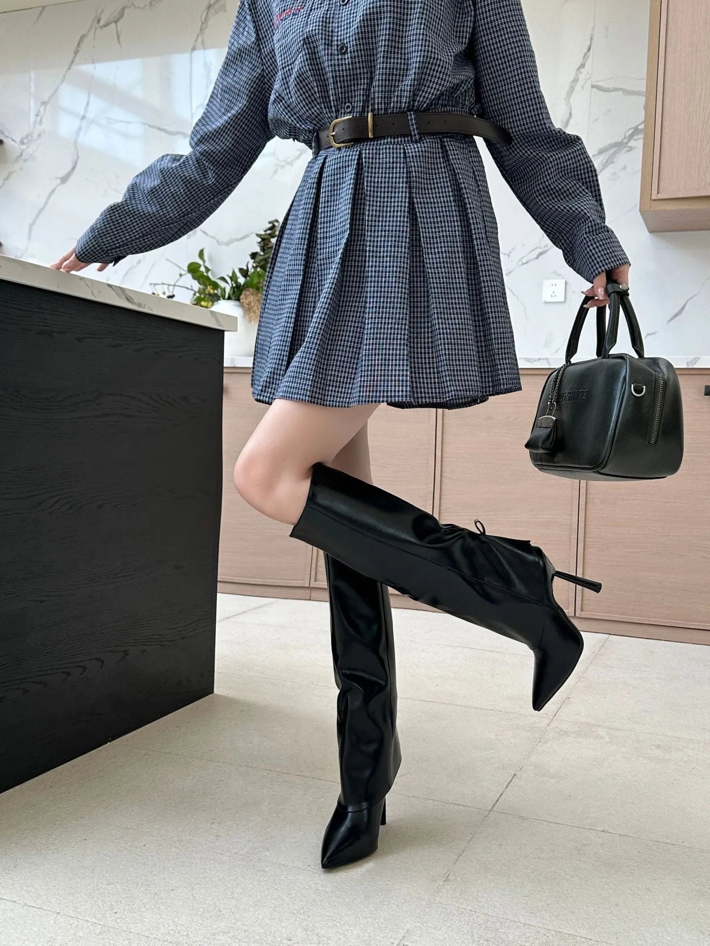 Black high-heel boot with integrated leg warmer, stiletto heel, pointed toe, and flanging detail.