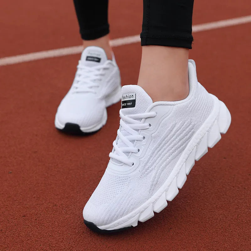 Women's low-top flat sneakers with cross-strap design in black and white colours
