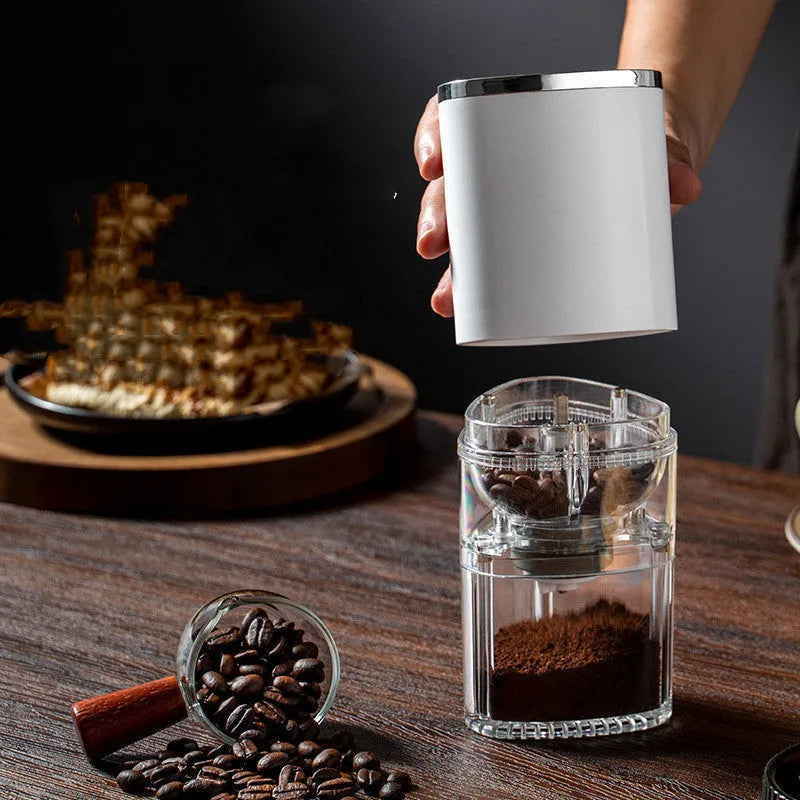 Black and white portable electric coffee grinder with USB charging cable on a kitchen counter.