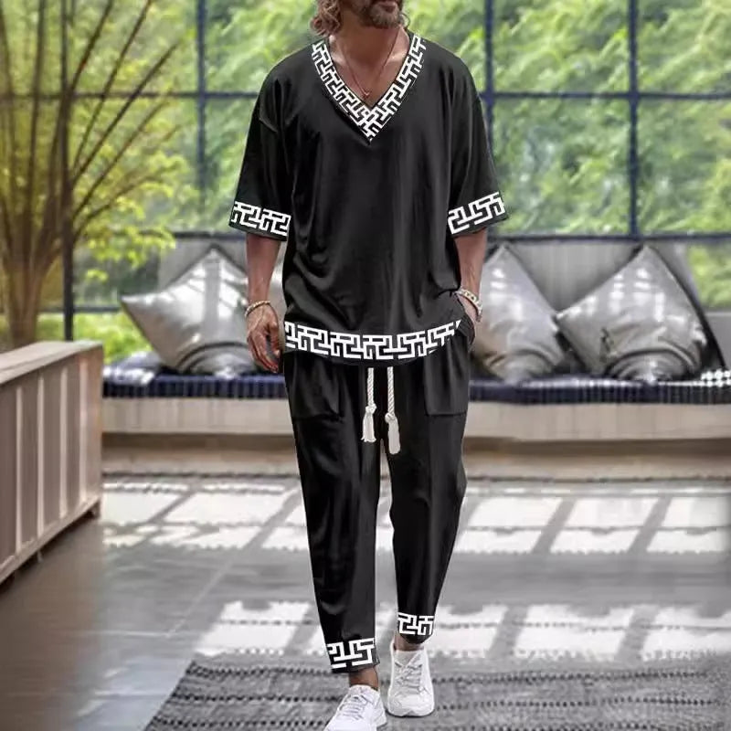 A person wearing a V-neck cropped sleeve jacket and matching trousers in a light colour.