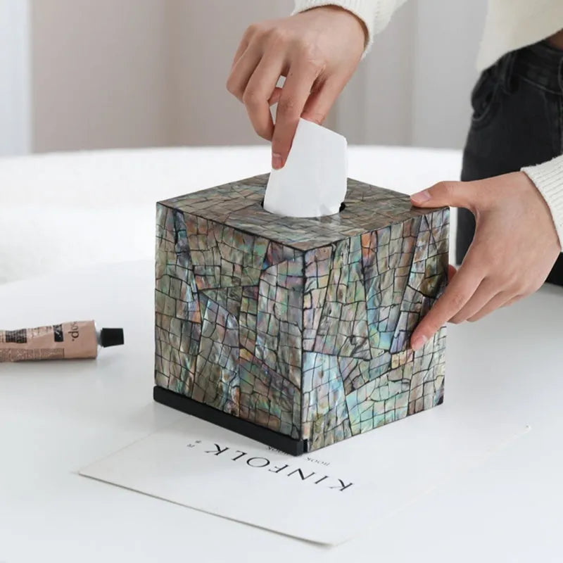 A black rectangular shell tissue box holder with a removable lid on a wooden coffee table.