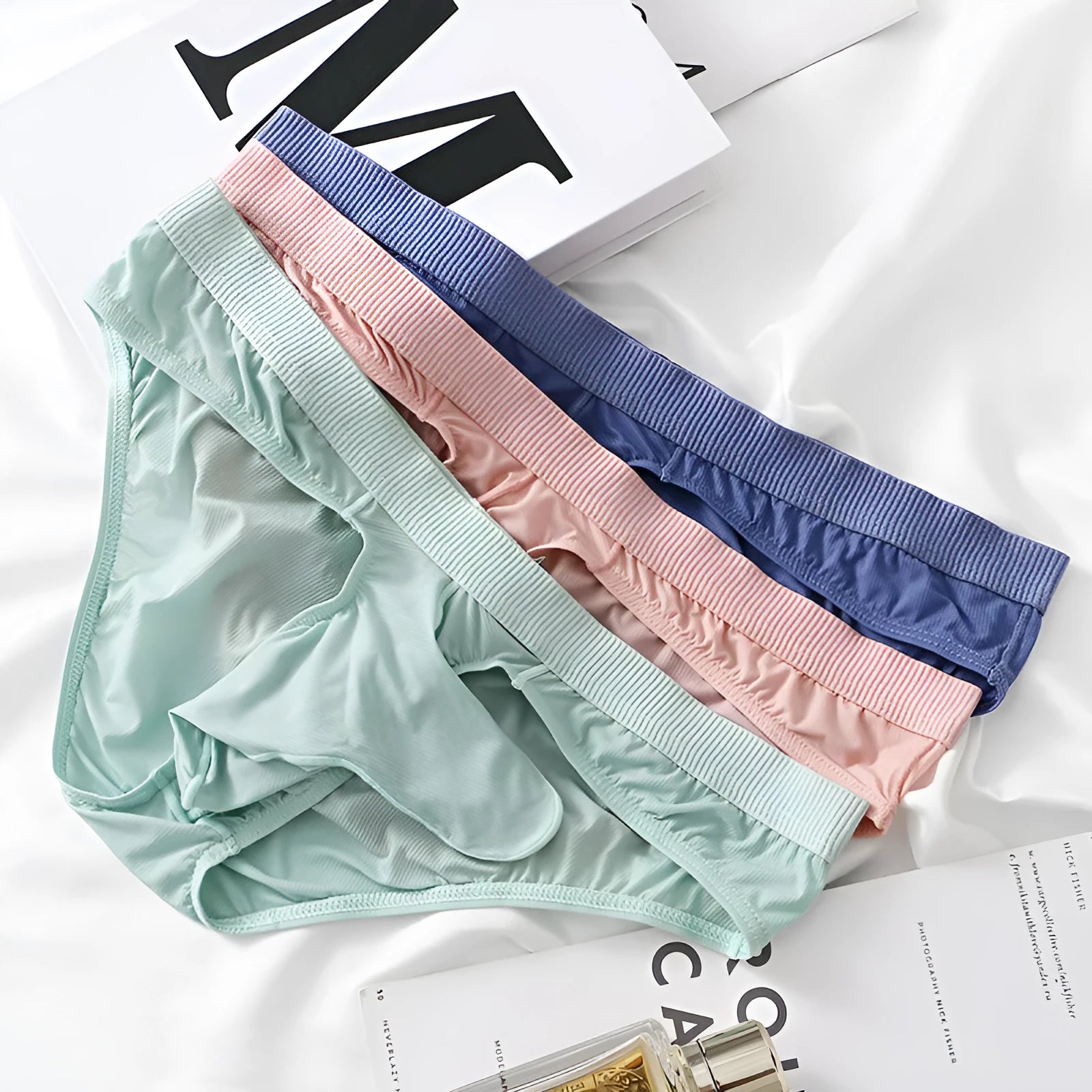 Men's low waist briefs underwear in ice silk nylon fabric on a colour swatch showing black, grey, purple blue, light green and pink.