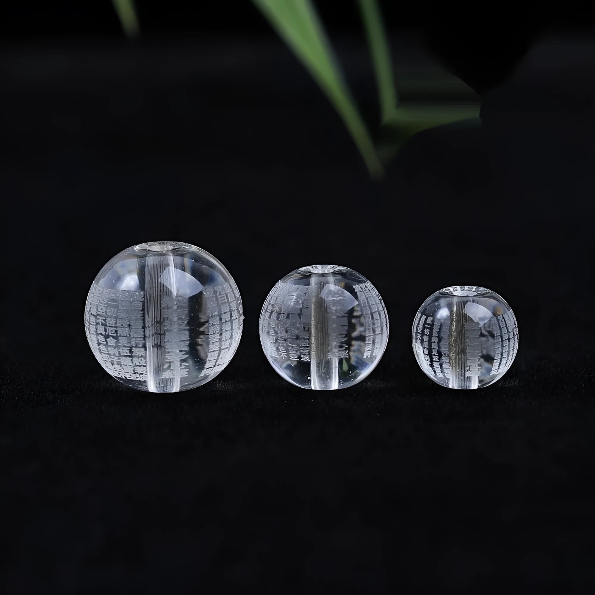 Ten 10mm round crystal prayer beads with Heart Sutra design, polished glass finish, scattered on a surface.