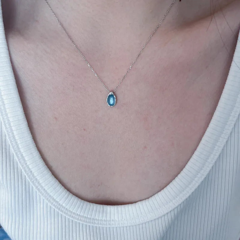 Geometric navy blue water droplet pendant necklace on a platinum-coloured adjustable chain.