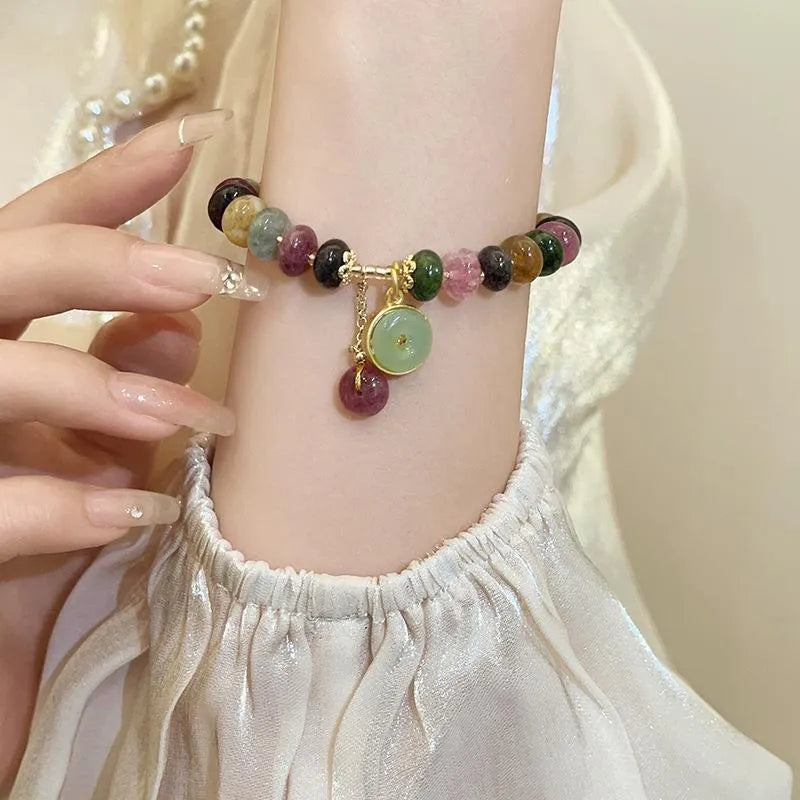 Colourful tourmaline beaded bracelet with geometric abacus beads and a rabbit pendant on a white background.