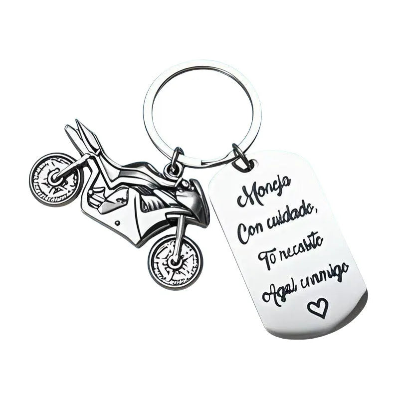 Stainless steel motivational motorcycle keychain with flannel storage pouch on a grey background.