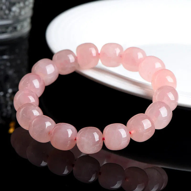 Pink natural crystal barrel bead bracelet with geometric beads on an elastic cord.