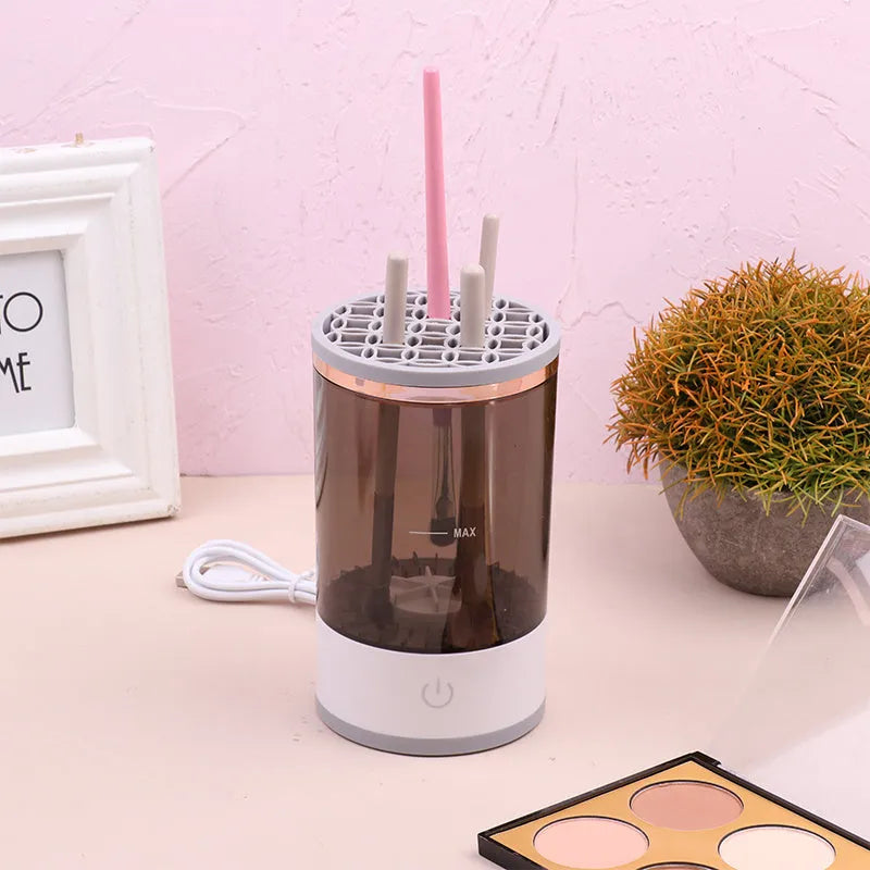 Grey and white electric makeup brush cleaner with USB charging cable on a wooden surface