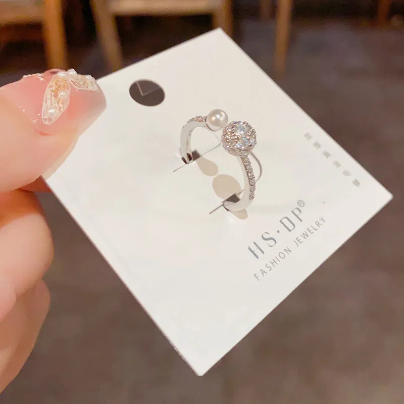 Open-end pearl ring with round zircon stone in gold or silver colour, showing geometric shape and thick real gold plating.
