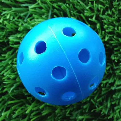 Hollow plastic golf practice ball in orange colour on indoor surface