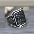 Black alloy ring with copper inlay detail and a central zircon stone on a finger.