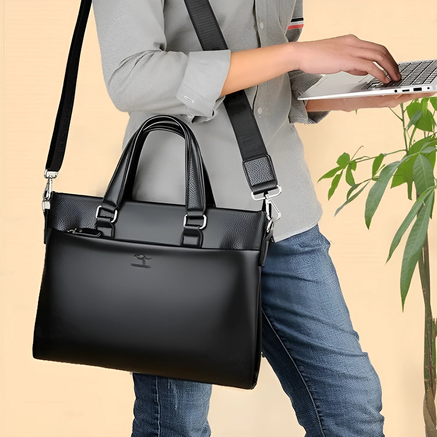 Men's black PU leather shoulder messenger bag with splicing detail on a table
