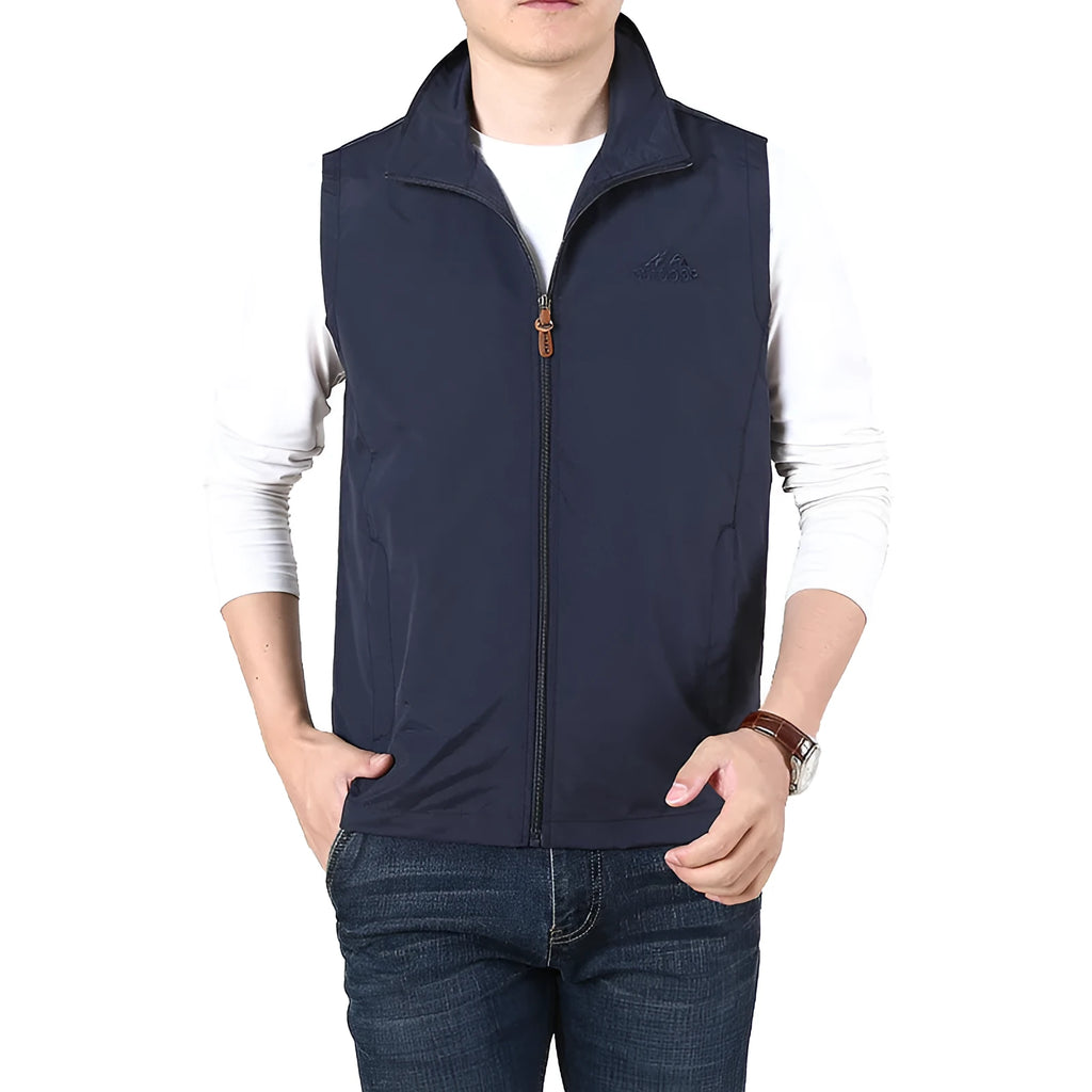A man wearing a thin khaki coloured waistcoat vest with side seam pockets, shown in a casual setting.