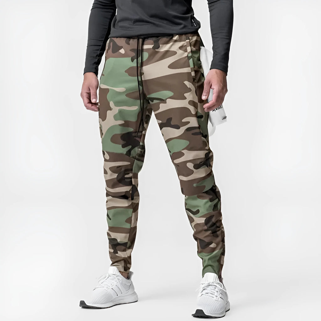 Men's loose grey fitness trousers with elasticated ankle ties on a gym floor.