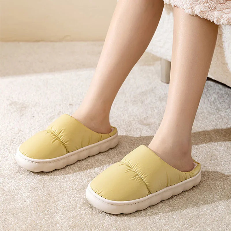 A pair of blue down cotton slippers with a thick sole, artificial leather upper, and plush lining for indoor winter wear.